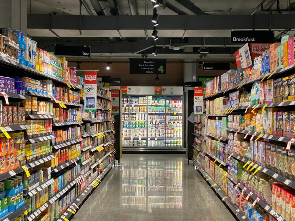 Grocery Store aisle with cooler at the end of the aisle containing beverages