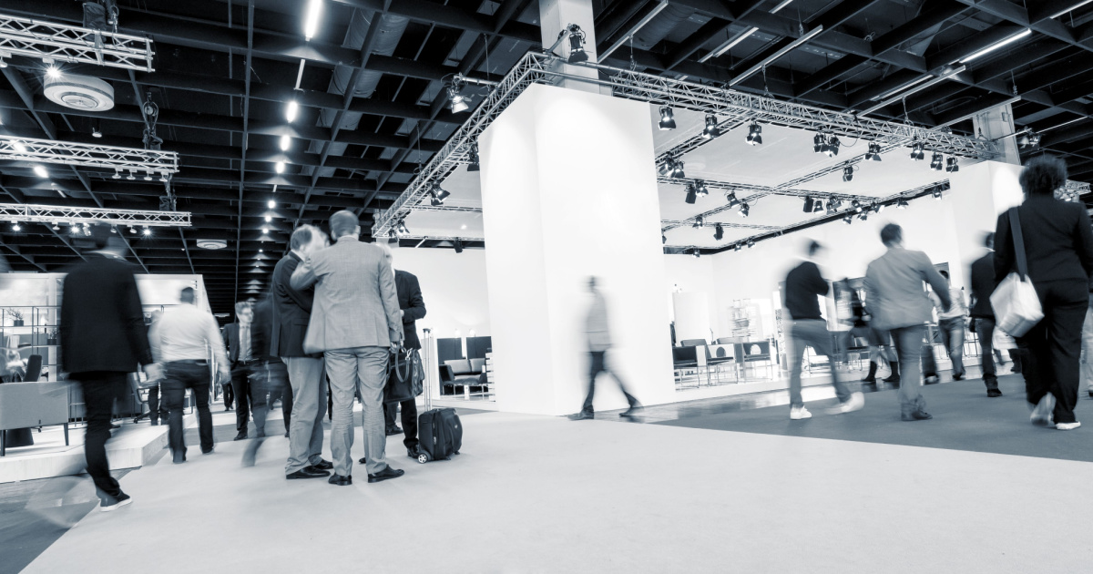 black and white image of people walking around a tradeshow