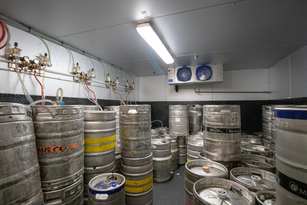 Inside of a grocery store beer cooler where numerus kegs of beer are stored