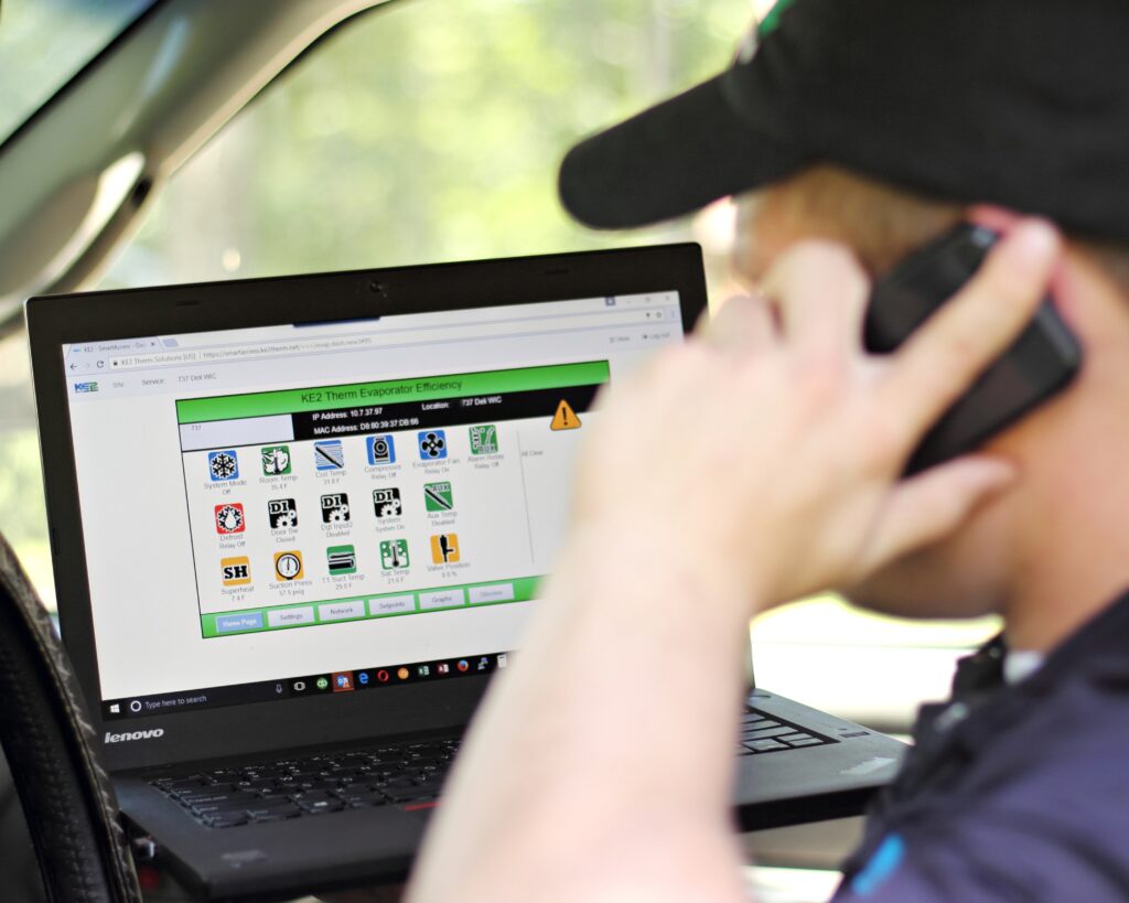 Man talking on phone while looking at computer screen showing alarm test