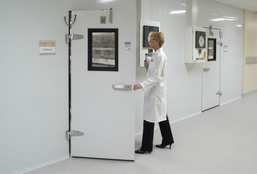 scientist walking through large walk-in door to a stability chamber